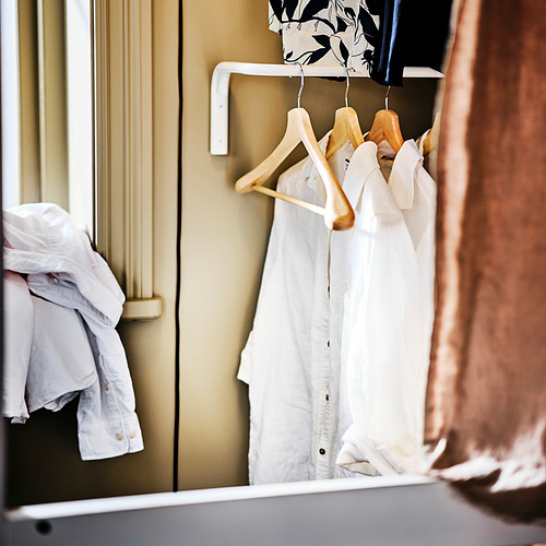 Perchas de ropa en un armario. Las perchas de madera sujetan las camisas y la chaqueta, evitando las arrugas y manteniendo la forma.