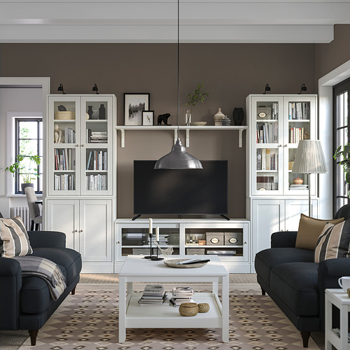 Sala de estar moderna con muebles HAVSTA: puertas de vidrio, banco de televisión, sofás, mesa de café contra la pared oscura.