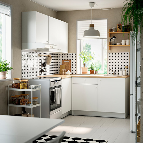 Cocina moderna: gabinetes blancos, encimera de madera, placa para salpicaduras de lunares, electrodomésticos de acero inoxidable, plantas.