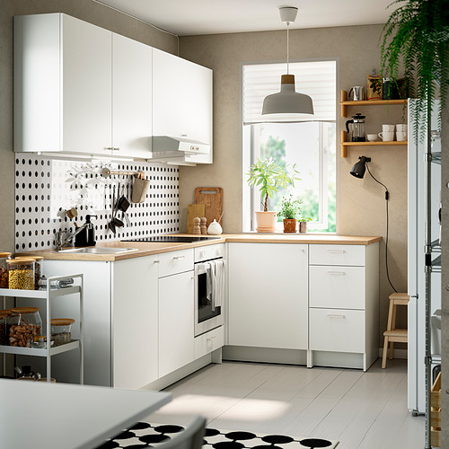 Cocina moderna en forma de L con gabinetes blancos, encimeras de roble y placa para salpicaduras estampada. Suelo en blanco y negro, con decoración y vegetación.
