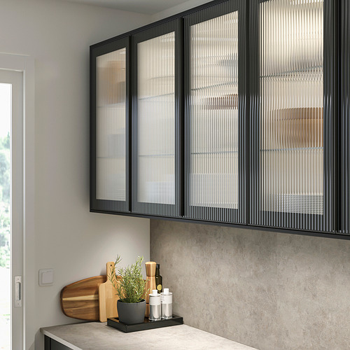 Cocina moderna con gabinetes de vidrio negro HEJSTA, líneas elegantes, encimera gris y planta.
