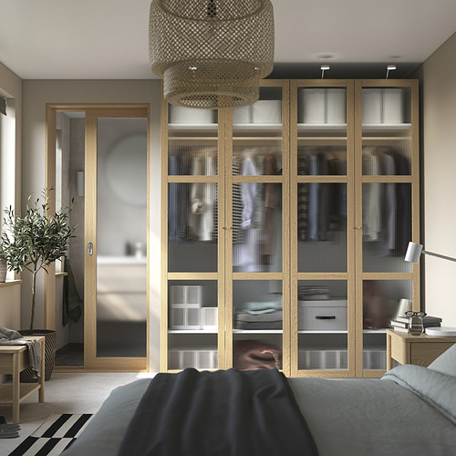Armario de madera con vidrio esmerilado, cama azul, lámpara redonda, planta, decoración minimalista.