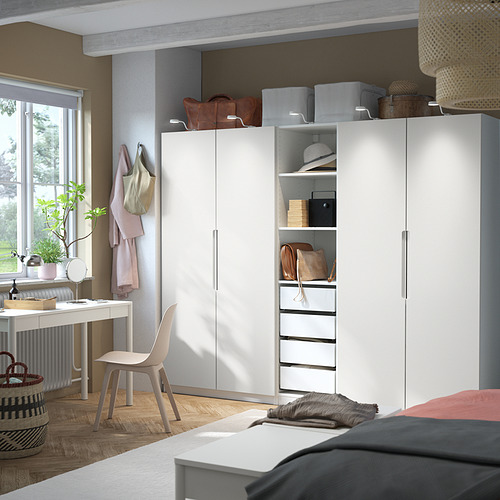 Dormitorio moderno con armario PAX, escritorio y silla gris. Armario alto con estantes y cajones, luz natural.