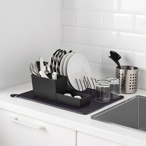 Fregadero de cocina con escurridor de platos y alfombra de secado. El escurridor contiene platos, cubiertos y tazas. La colchoneta atrapa las gotas.