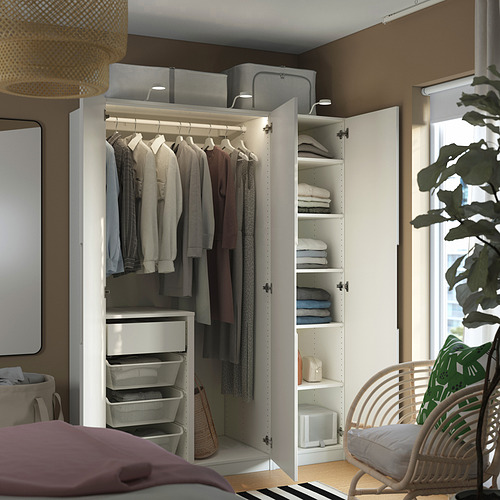 Dormitorio moderno con armario PAX, ropa cuidada y accesorios. Silla y planta de mimbre.