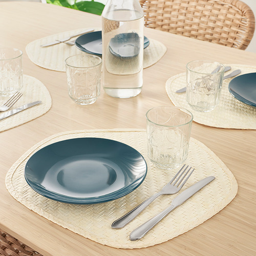 Juego de mesa de madera con platos azules, cubiertos, vasos de vidrio y manteles individuales tejidos.