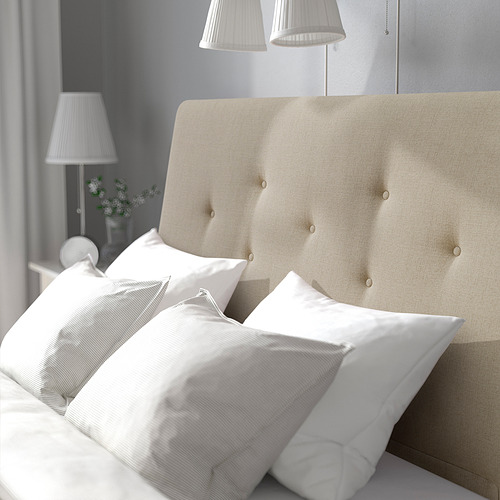 Cama con cabecero tapizado, almohadas blancas, lámparas en mesitas de noche.