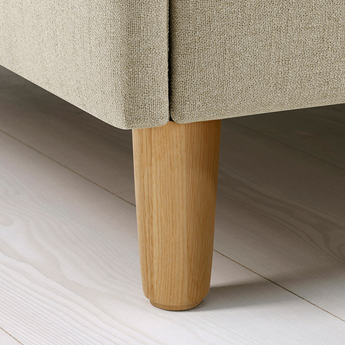 La pata de la cama hecha a mano en primer plano, la madera clara resistente soporta un marco tapizado de felpa sobre un piso elegante.