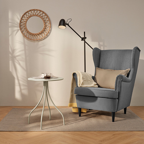 Sala de estar moderna con silla, mesa auxiliar, lámpara y espejo. Acogedora configuración de suelo de madera.
