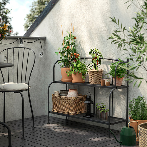 La estantería negra de LÄCKÖ alberga hierbas y plantas en maceta, y el balcón tiene una silla.