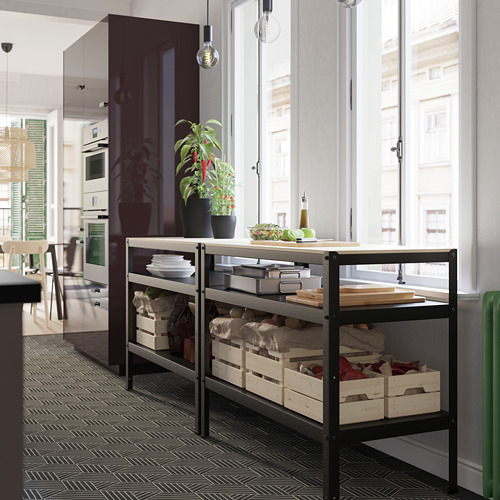 Estante de almacenamiento de metal negro con cajas de madera y artículos de cocina junto a la ventana.