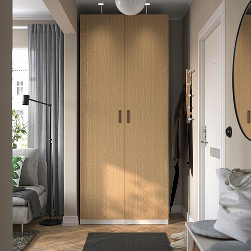 Moderno armario PAX de color marrón claro en una acogedora habitación, entre la ventana y la puerta, que ofrece un amplio espacio de almacenamiento y se combina a la perfección con la decoración.