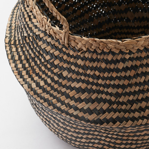 Cesta tejida de pastos marinos, asas hacia arriba, que muestra una artesanía intrincada y una textura natural.