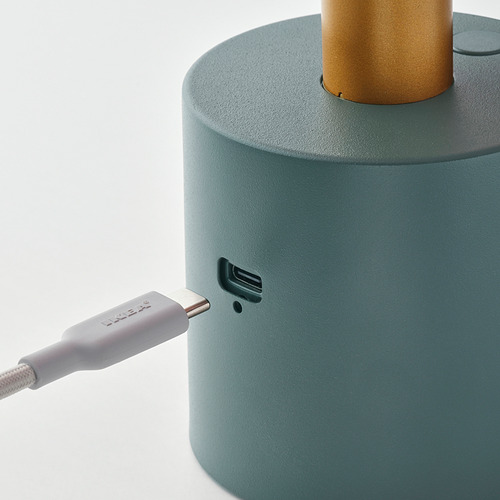 Lámpara portátil verde con puerto de carga usb-c, que muestra un cable usb-c morado conectado.
