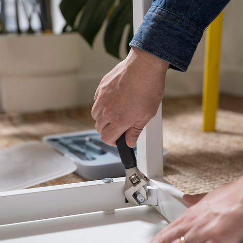 La persona usa el martillo de la caja de herramientas TRIXIG para ensamblar muebles, mostrando la funcionalidad de bricolaje.