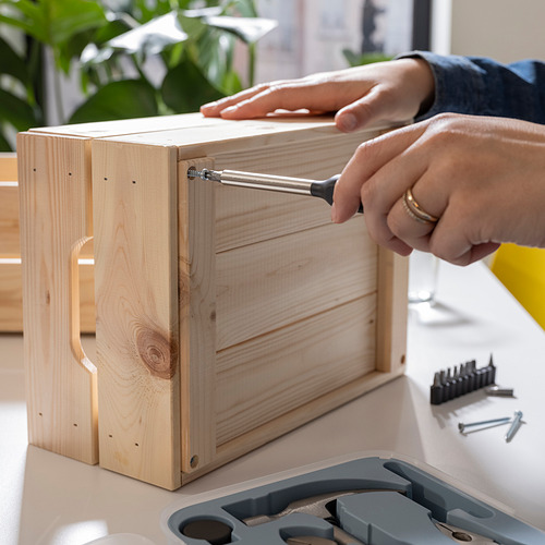 Persona que usa un destornillador de la caja de herramientas TRIXIG para ensamblar una caja de madera.