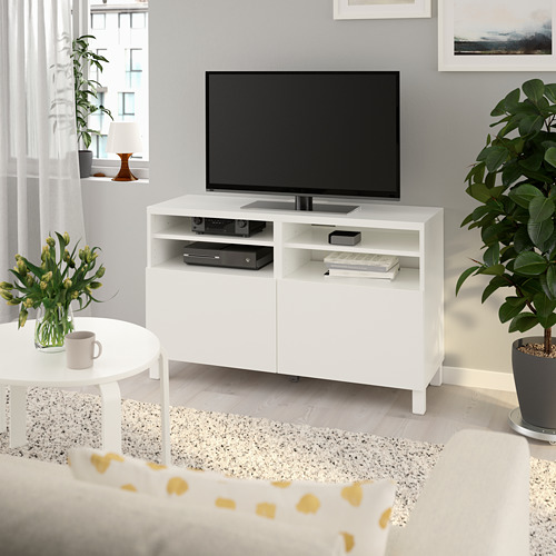 Mueble de tv blanco BESTÅ con televisor de pantalla plana, estantes ajustables, electrónica, jarrón, planta, cuadro de pared.