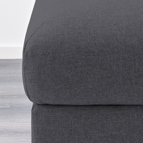 Primer plano de un moderno sofá de tela gris oscuro, que muestra sus líneas limpias y detalles de tapicería de alta calidad.