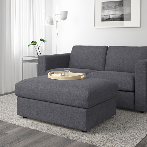 Moderno sofá modular gris con otomana, bandeja de madera y lámpara lateral. Almacenamiento y portabebidas.