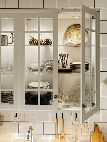 Mueble de cocina moderno con puertas de vidrio, iluminado por luz MITTLED, exhibiendo platos, tazones y vasos, organizados y visualmente atractivos.