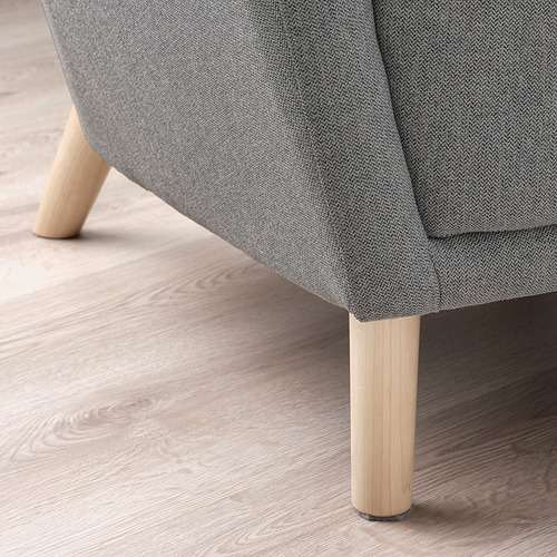 Primer plano de un sillón orejero de tela gris, mostrando sus robustas patas de madera y costuras de primera calidad sobre un suelo de madera.