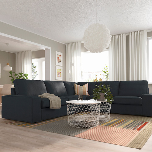 Moderno salón con gran sofá KIVIK, alfombra, cojines y luz natural.