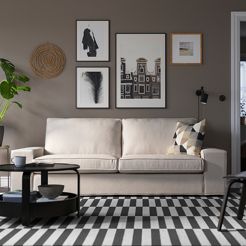 Sala de estar moderna con sofá KIVIK, mesa de centro, alfombra a cuadros y lámpara de pie.