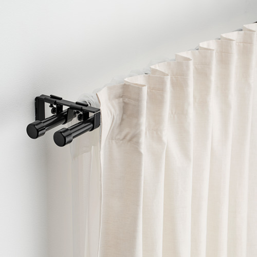 Juego de barras de cortina negras con cortinas, soportes y remates blancos unidos a la pared.