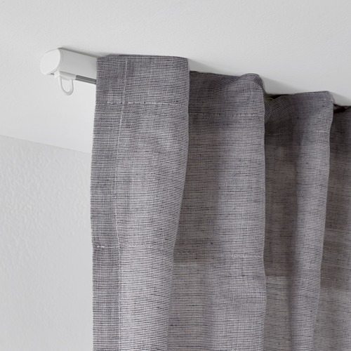Barra de cortina blanca montada en el techo con cortinas texturizadas grises, que muestra el sistema de rieles ajustables de FRAMFUSIG.