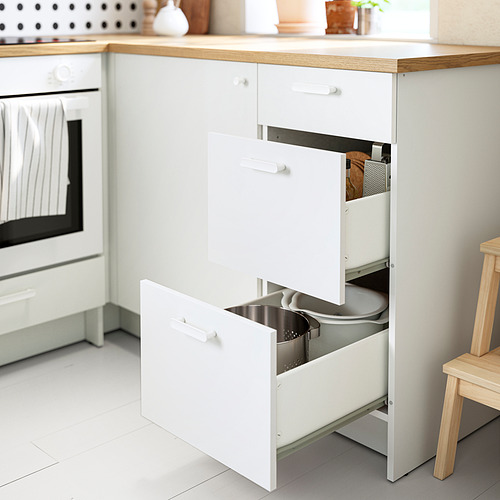 Cocina moderna con mueble bajo blanco KNOXHULT, tres cajones abiertos que exhiben utensilios organizados, encimera de madera clara.