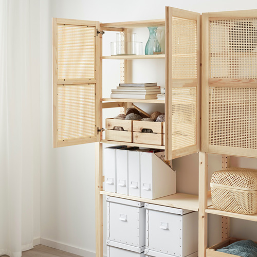 Armario de madera natural con puertas de bambú que se abren, dejando ver estantes con cajas de almacenamiento, libros y una jarra.