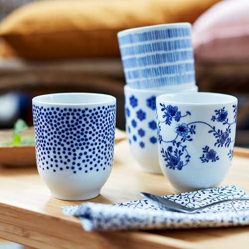 Cuatro tazas estampadas en azul y blanco sobre una superficie de madera, una con lunares, otra con diseños florales y dos con patrones de rayas.