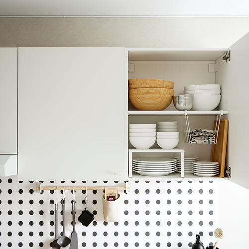 Armario de cocina abierto con tazones, platos y utensilios cuidadosamente organizados en estantes y ganchos. Diseño blanco y de madera con salpicadero de lunares.