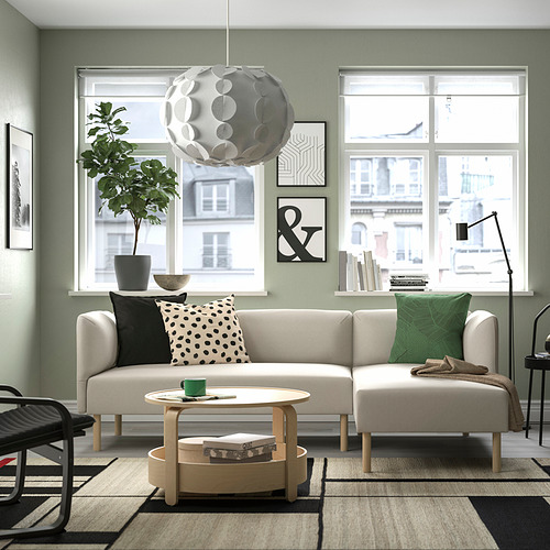 Salón moderno con sofá LILLEHEM beige. Grandes ventanales, planta, luz única. Decoración minimalista con acentos en blanco y negro.