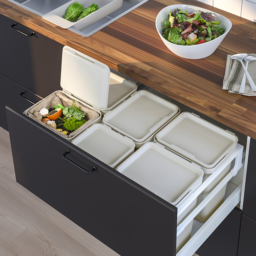 Encimera de cocina con ensaladera y cubos de clasificación de residuos HÅLLBAR abiertos en el cajón: cuatro blancos, uno con compostables.