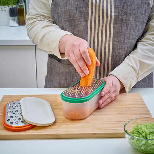 La persona ralla comida de naranja en un recipiente sellado sobre una tabla de madera.
