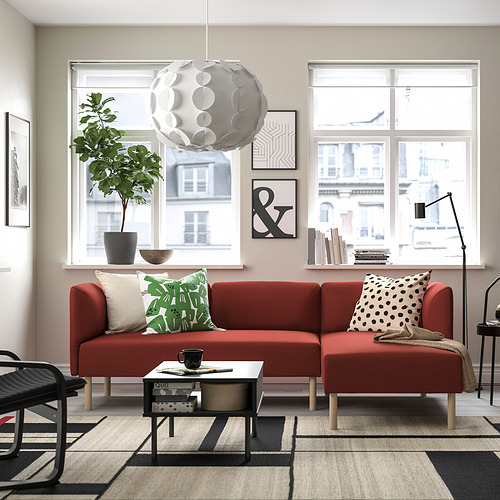 Moderno salón con sofá LILLEHEM rojo, grandes ventanales, planta y mesa de centro negra.