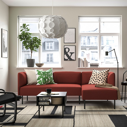 Sofá LILLEHEM rojo vibrante con almohadas verdes/blancas, alfombra, lámpara colgante, elegante mesa de centro, planta, cuenco, arte de pared.