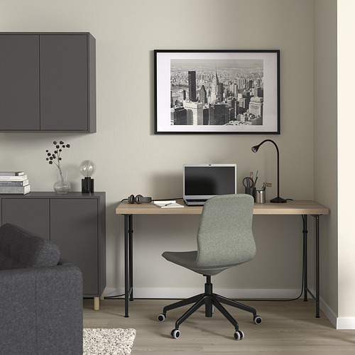 Moderna oficina en casa con mesa SPÄND, silla gris, decoración minimalista y arte de paisajes urbanos.