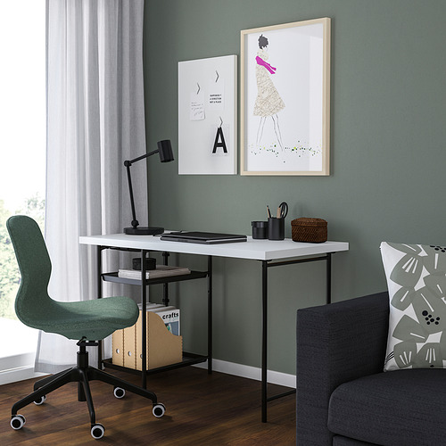 Configuración de la oficina en casa: escritorio LAGKAPTEN blanco con silla negra, sofá gris, láminas artísticas, lámpara, suelo de madera.
