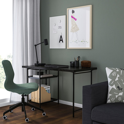 Oficina esquinera verde con mesa SPÄND, lámpara, arte, sillón gris y gran ventanal.