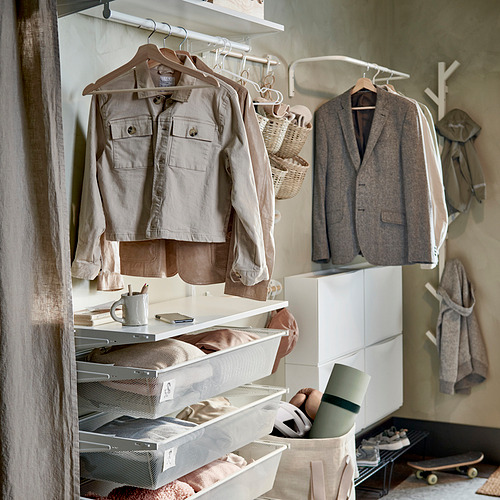 Armario organizado con perchas BUMERANG beige de madera maciza, con capacidad para chaquetas y vaqueros, cajones de malla blanca y un monopatín.