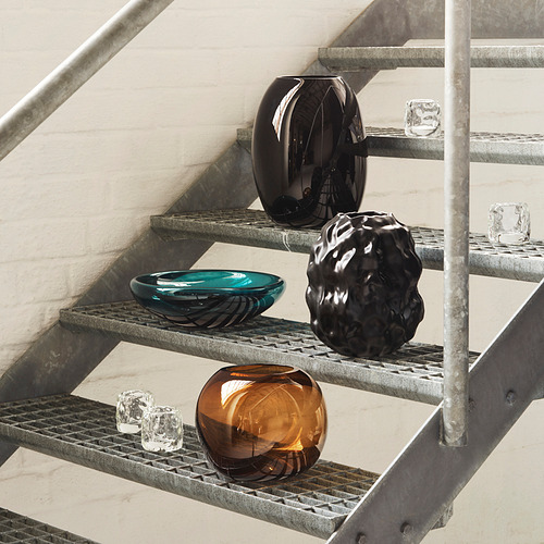 Escaleras con jarrones multicolores. Negro, verde azulado, marrón; burbujeante, brillante, mate. Jarrones transparentes más pequeños cerca.