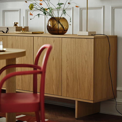 Aparador de madera de diseño minimalista, con patas ajustables y puertas de apertura a presión, que proporciona un amplio espacio de almacenamiento, rematado con un jarrón de flores.