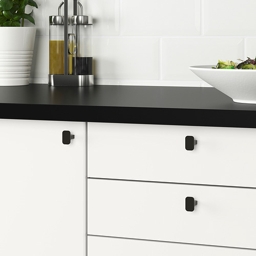 Muebles de cocina modernos con pomos HACKÅS negros, lisos al tacto, sobre cajones blancos con encimera negra.