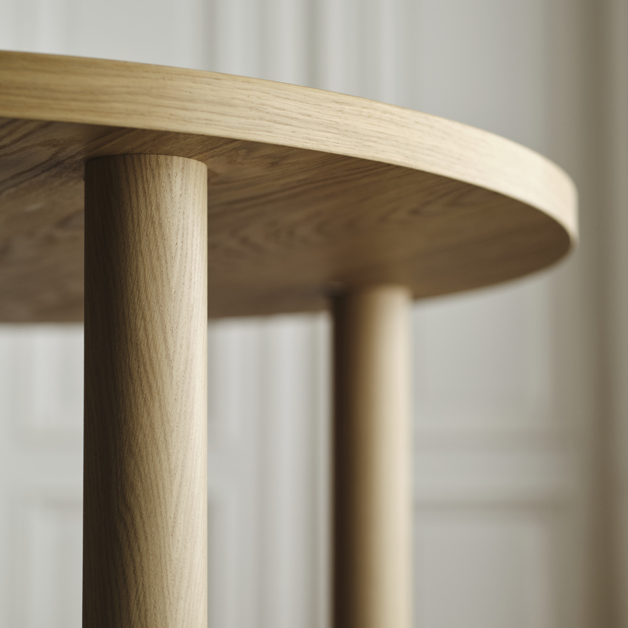 Primer plano de una elegante mesa redonda de madera con acabado liso, destacando su calidad artesanal y su textura de madera natural.