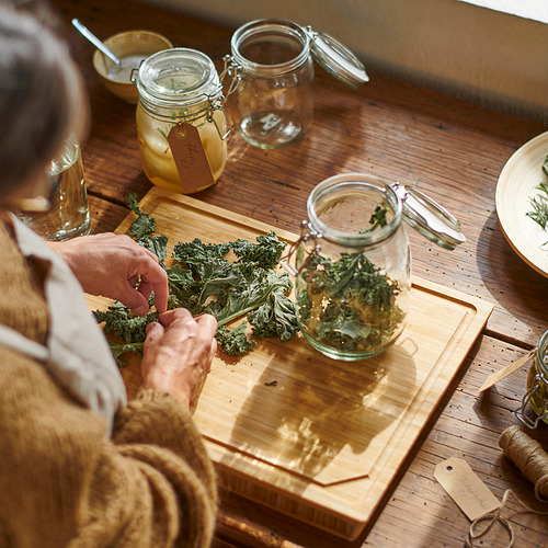 La persona está encurtiendo verduras en una tabla de cortar de madera. Para la conservación se utiliza un tarro de vidrio con cierre hermético con cierre hermético.