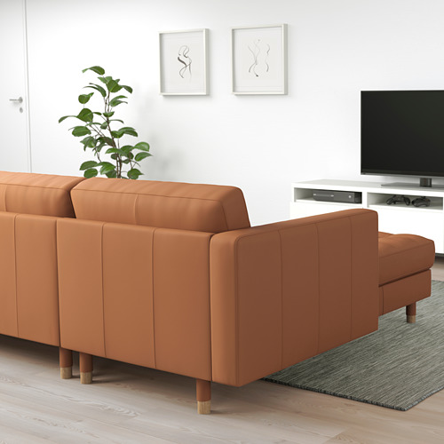 Moderno salón minimalista con gran sofá modular LANDSKRONA de color óxido, patas de madera, cojines suaves. Encaja perfectamente junto a la televisión y la alfombra verde.