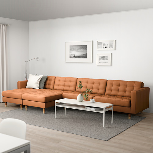 Sala de estar moderna: sofá con sección de cuero tostado, mesa de centro blanca, alfombra gris, arte de pared.