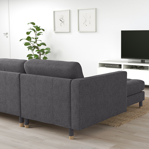 Sofá LANDSKRONA gris oscuro, diseño moderno y minimalista, grande, con patas de madera, cerca de una consola de tv blanca y planta.